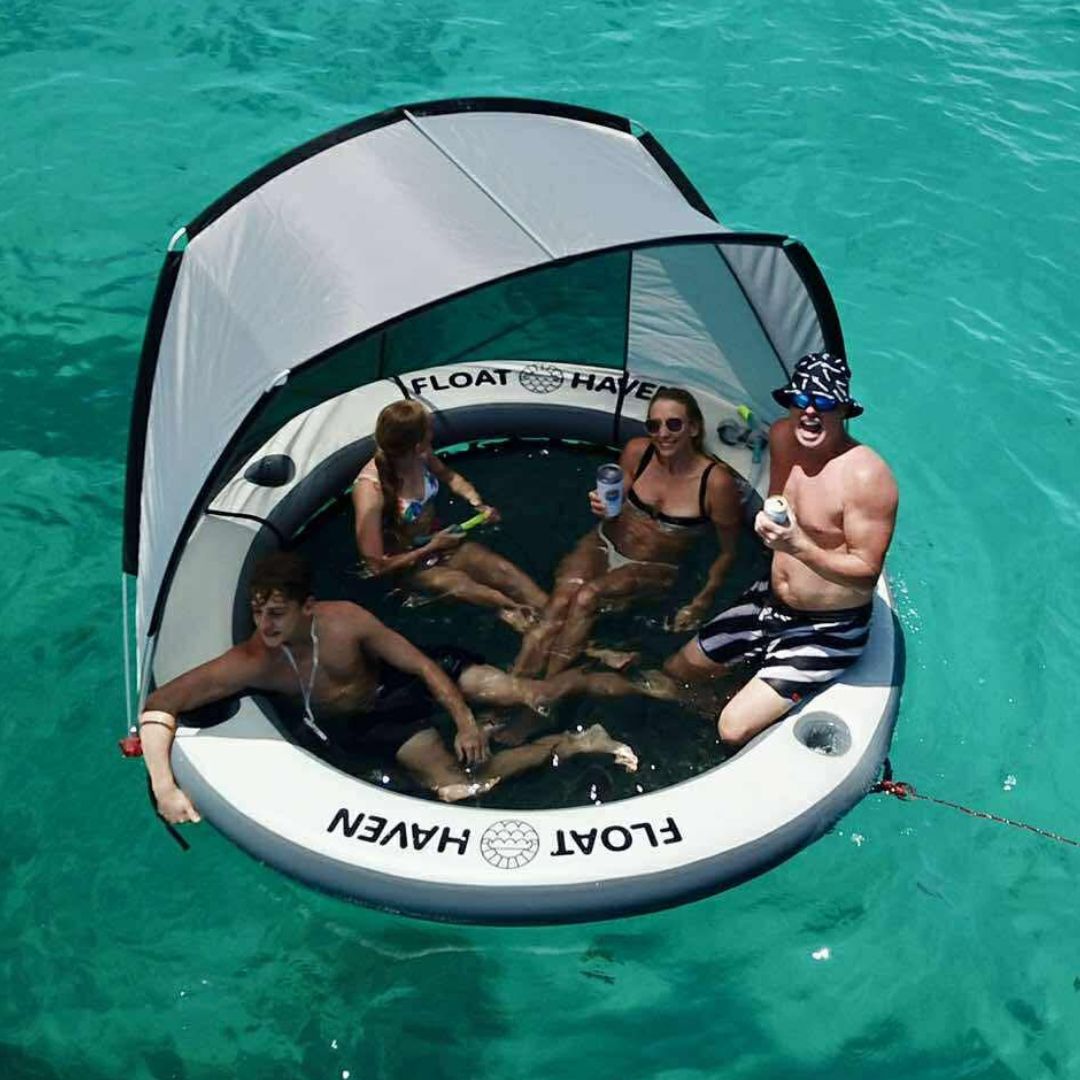People enjoying a Float Haven inflatable island with Shade in clear blue water 